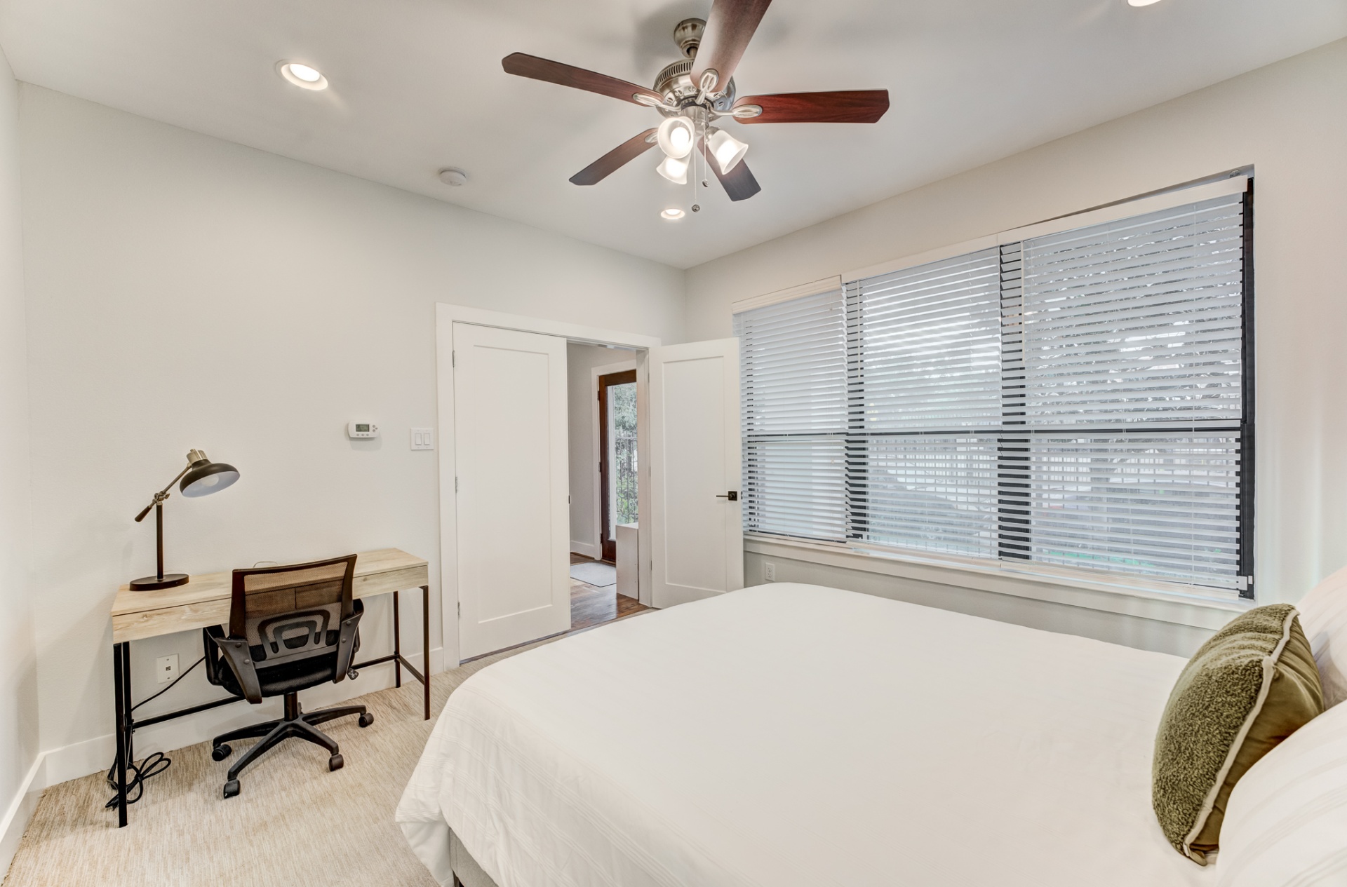 First-floor bedroom with queen bed, ceiling fan, and desk workspace