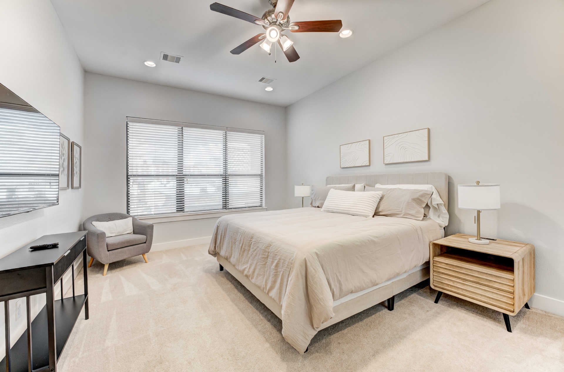 Primary bedroom with king bed, ceiling fan, and reading chair