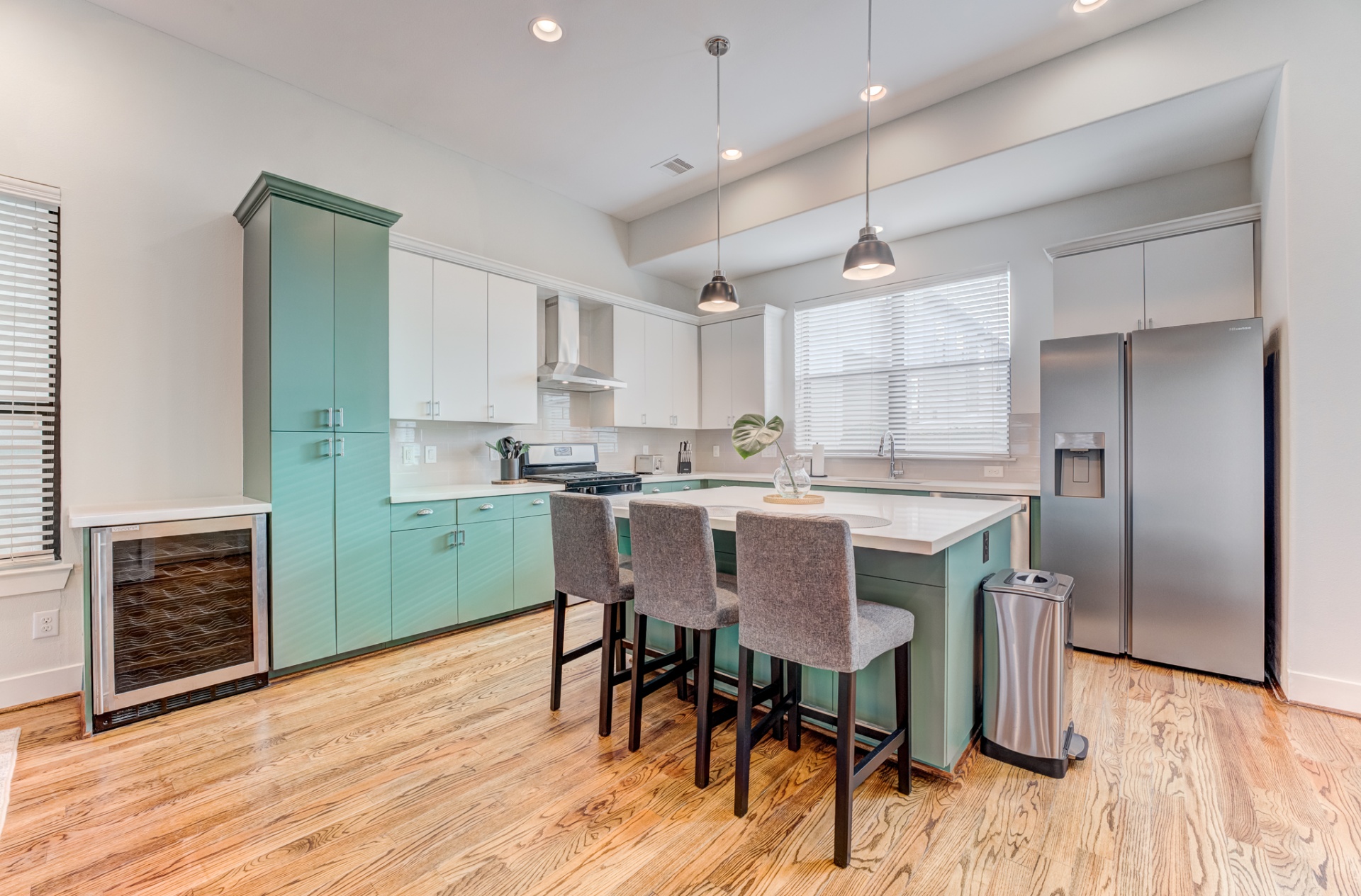 Open kitchen with teal cabinetry and quartz island
