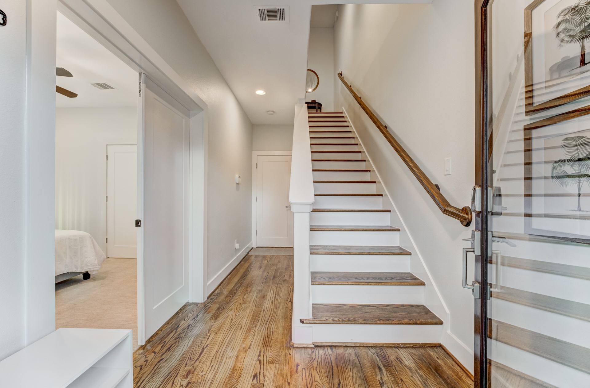 Open stairwell with red oak floors leading upstairs