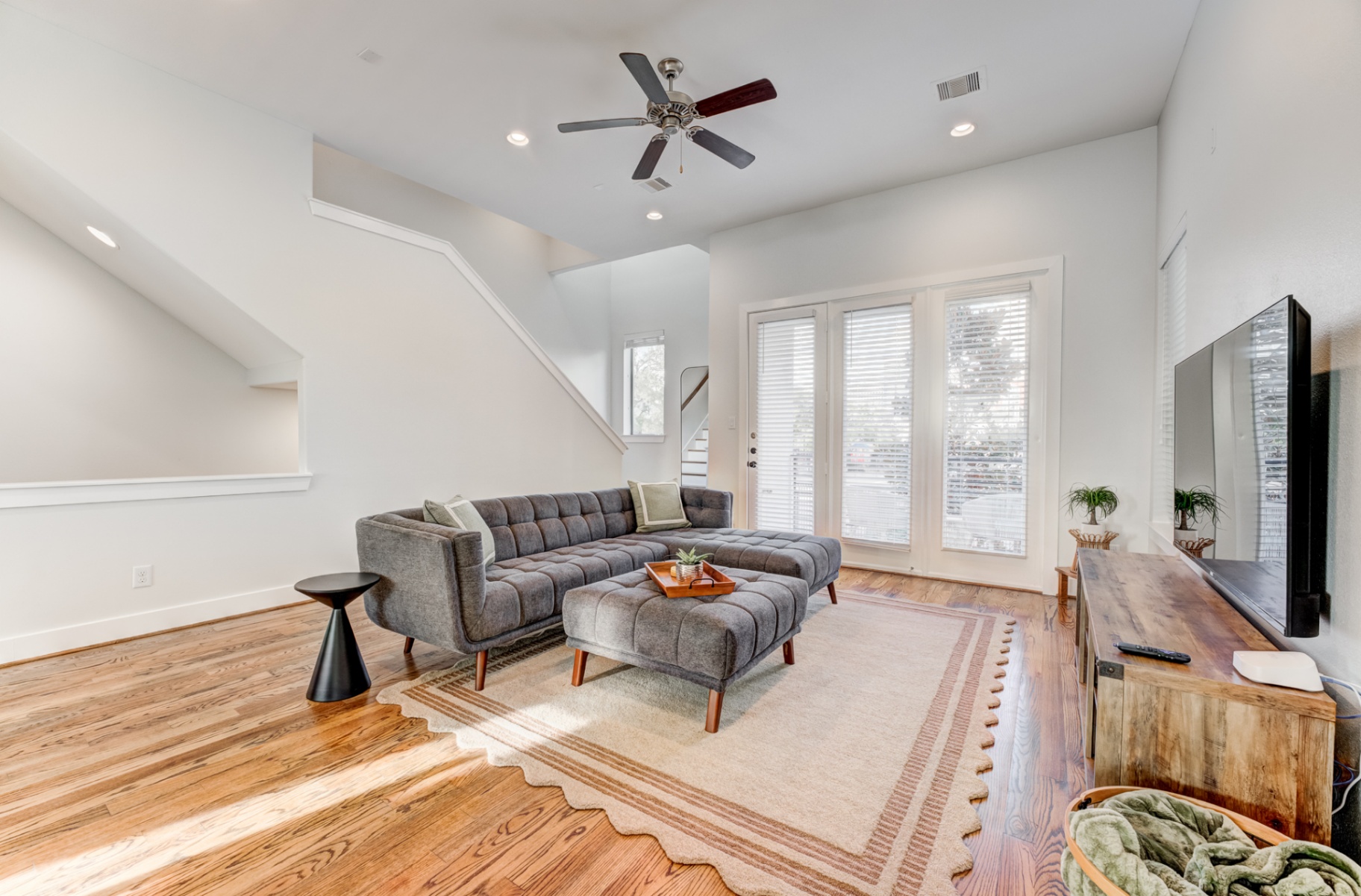 Bright living room with sectional, tall ceilings, and stairwell