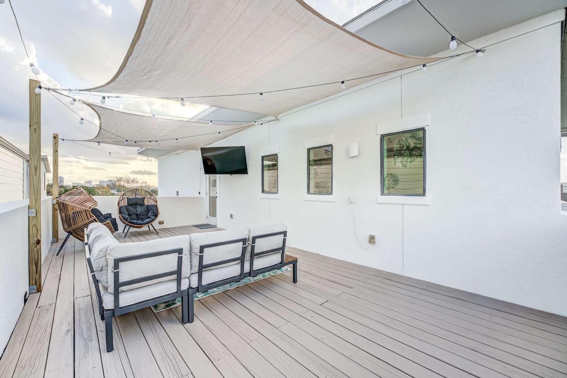 Rooftop deck with shaded sectional, lounge chairs, and TV