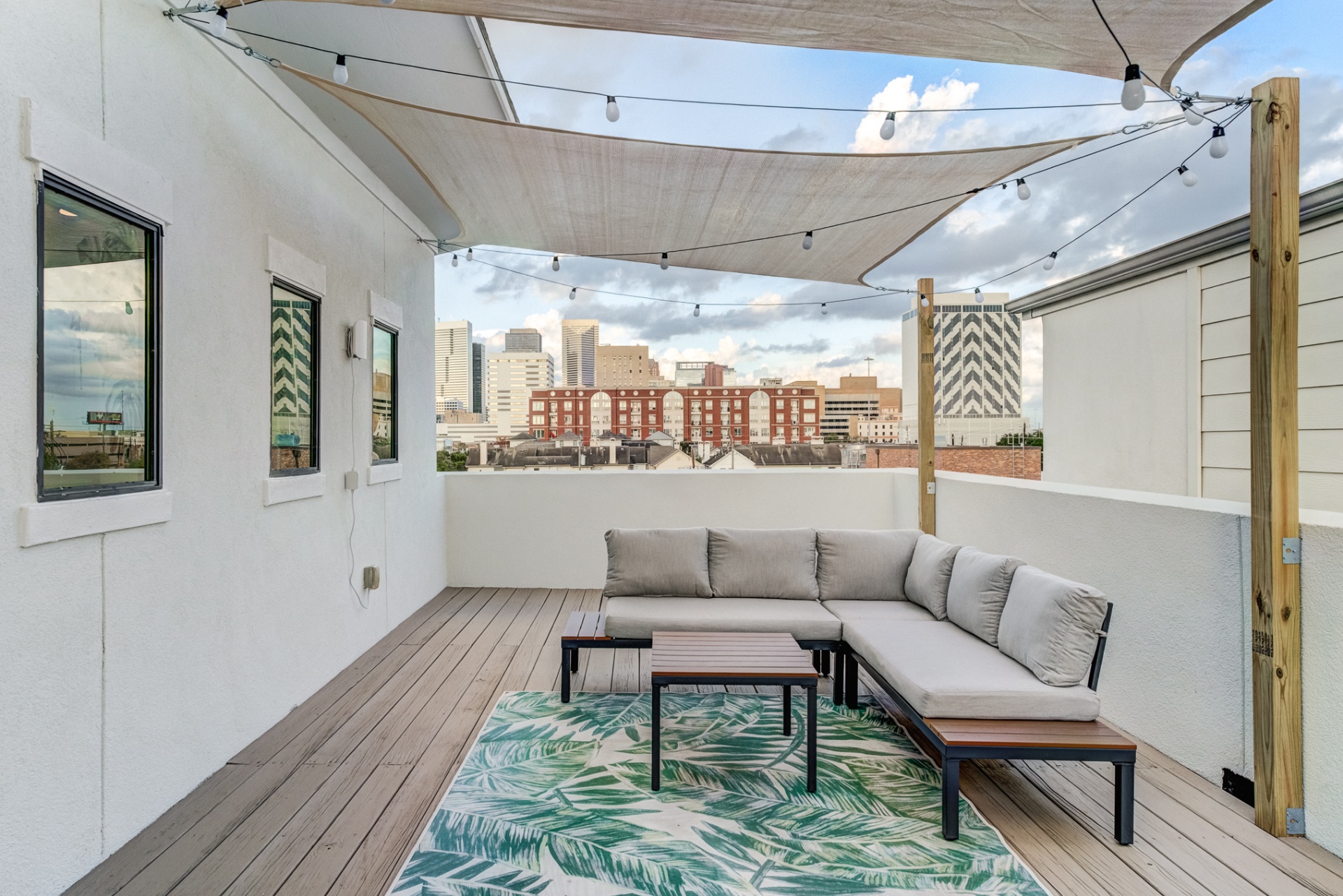 Rooftop sectional under shade sails with string lights and city views